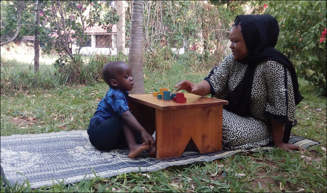 female teacher using blocks too teach a small boy